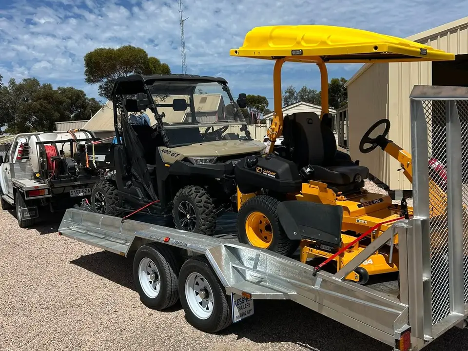 Spray-rig ute, side-by-side and yellow zero-turn mower loaded on a trailer